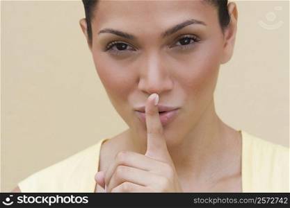 Portrait of a young woman putting her finger on her lips