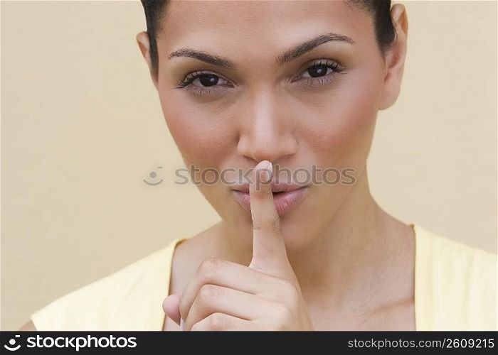 Portrait of a young woman putting her finger on her lips