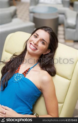Portrait of a young woman reclining on a chair and smiling