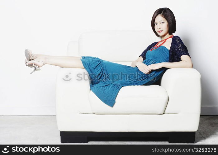 Portrait of a young woman reclining on an armchair