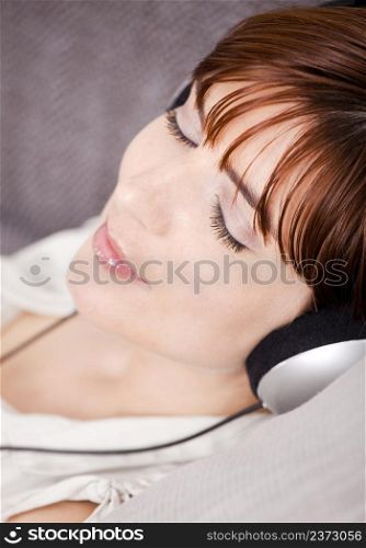 Portrait of a young woman relaxing and listening music with headphones