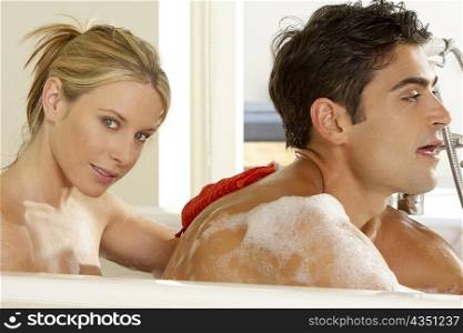 Portrait of a young woman scrubbing a young man&acute;s back