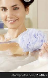 Portrait of a young woman scrubbing her arm with a bath sponge