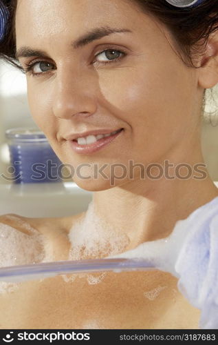 Portrait of a young woman scrubbing her body in a bathtub