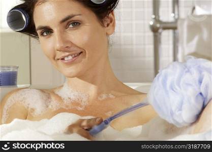 Portrait of a young woman scrubbing her body in a bathtub