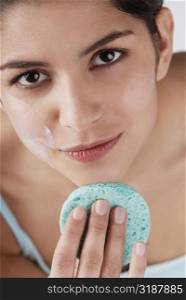 Portrait of a young woman scrubbing her chin with a sponge
