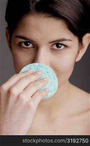 Portrait of a young woman scrubbing her nose with a sponge