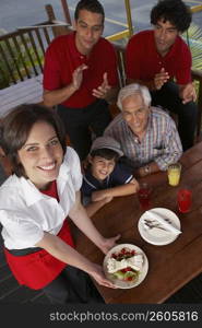 Portrait of a young woman serving dessert to a boy celebrating his birthday in a restaurant