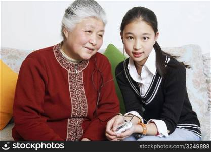 Portrait of a young woman sharing headphones with her grandmother