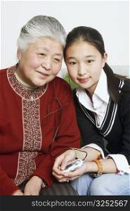 Portrait of a young woman sharing headphones with her grandmother