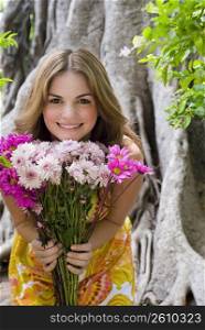 Portrait of a young woman showing a bouquet of flowers and smiling