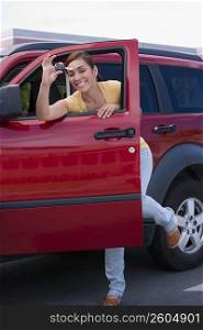 Portrait of a young woman showing a car key and smiling
