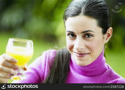 Portrait of a young woman showing a glass of juice