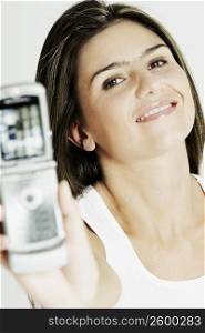 Portrait of a young woman showing a mobile phone