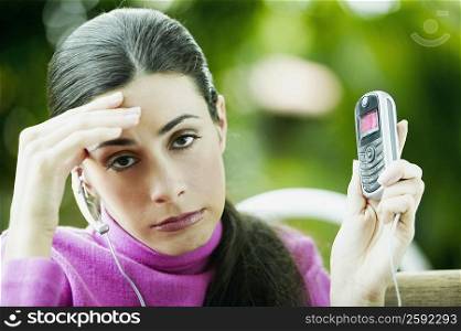 Portrait of a young woman showing a mobile phone and making a face