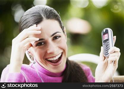 Portrait of a young woman showing a mobile phone and smiling