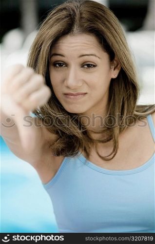 Portrait of a young woman showing thumbs down