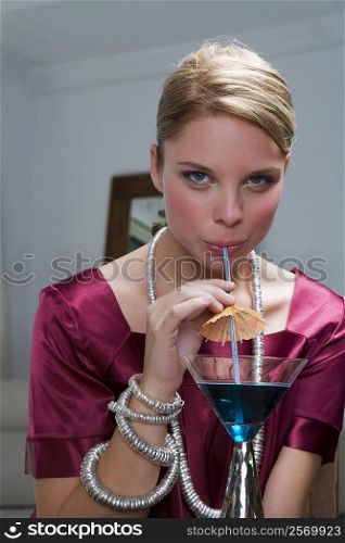 Portrait of a young woman sipping a cocktail