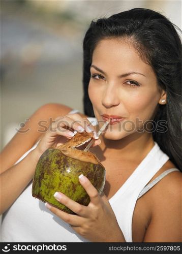 Portrait of a young woman sipping juice from a coconut
