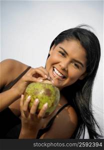 Portrait of a young woman sipping juice from coconut
