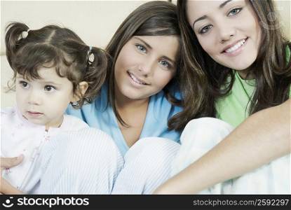 Portrait of a young woman sitting and her two sisters smiling