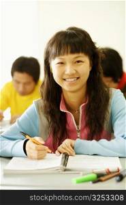 Portrait of a young woman sitting at a desk in the classroom and smiling