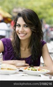 Portrait of a young woman sitting at a sidewalk cafe and smiling
