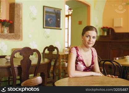 Portrait of a young woman sitting at a table