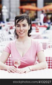 Portrait of a young woman sitting at a table in a sidewalk cafe