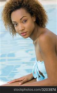 Portrait of a young woman sitting at the edge of a swimming pool