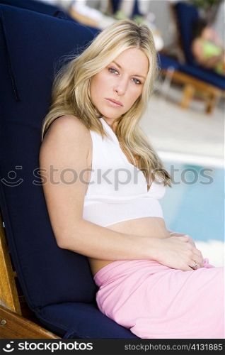 Portrait of a young woman sitting at the poolside