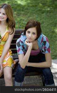 Portrait of a young woman sitting beside another young woman and thinking