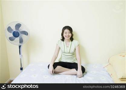 Portrait of a young woman sitting cross-legged on the bed