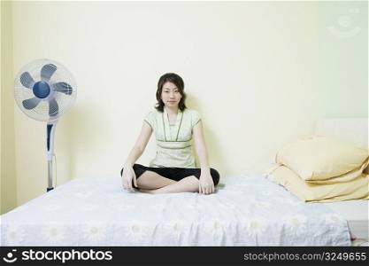 Portrait of a young woman sitting cross-legged on the bed