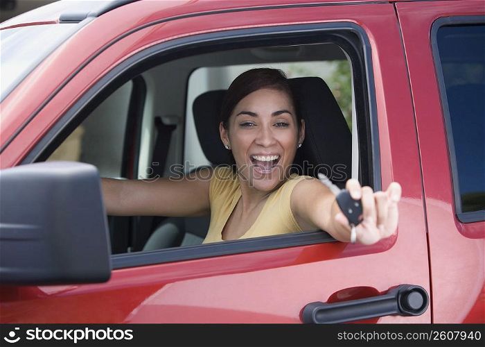 Portrait of a young woman sitting in a car and showing a car key