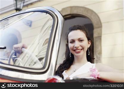 Portrait of a young woman sitting in a car and smiling