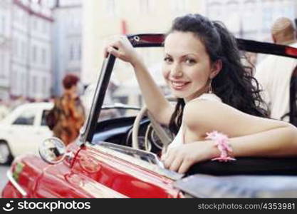Portrait of a young woman sitting in a car and smiling