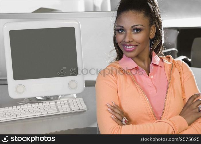 Portrait of a young woman sitting in a computer lab and smiling