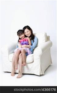 Portrait of a young woman sitting in an armchair with her daughter on her lap