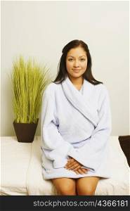 Portrait of a young woman sitting in bathrobe and smiling