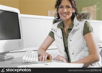 Portrait of a young woman sitting in front of a desktop PC and smiling