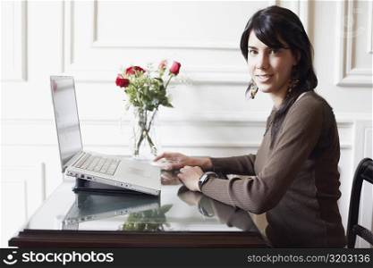Portrait of a young woman sitting in front of a laptop
