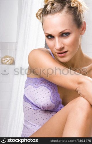 Portrait of a young woman sitting in the bathroom