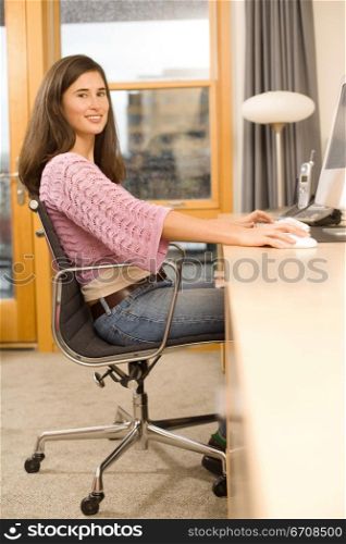 Portrait of a young woman sitting on a chair and using a computer