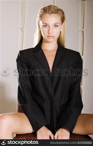 Portrait of a young woman sitting on a chair with her legs apart