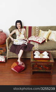 Portrait of a young woman sitting on a couch and holding a magazine