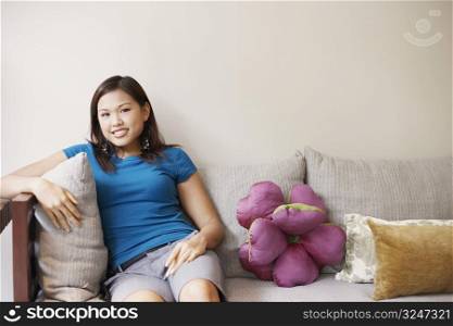 Portrait of a young woman sitting on a couch and smiling