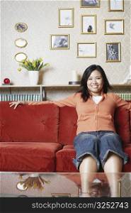 Portrait of a young woman sitting on a couch smiling