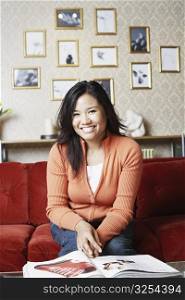 Portrait of a young woman sitting on a couch smiling