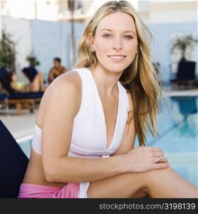 Portrait of a young woman sitting on a lounge chair at the poolside